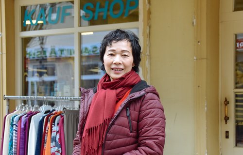 Eine Frau steht vor ihrem Laden und schaut in die Kamera.