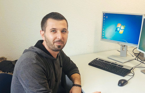 Ein junger Mann sitzt am Schreibtisch.