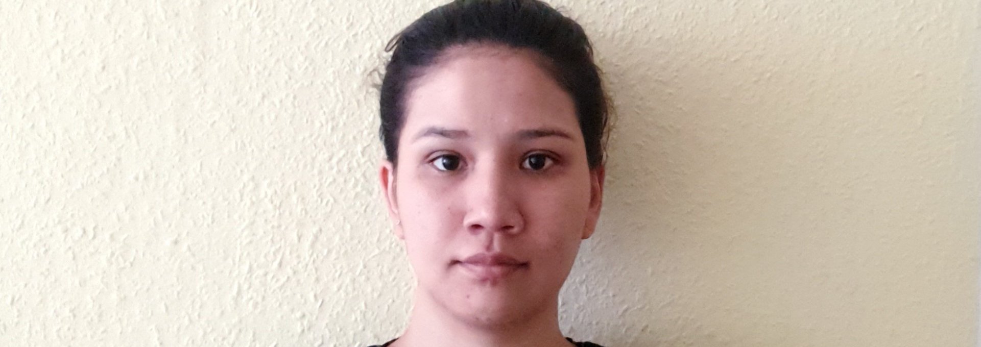 Eine junge Frau steht vor einer weißen Wand