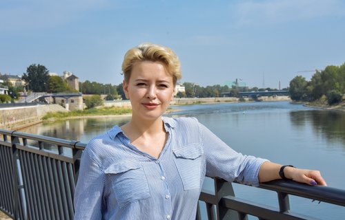 Eine junge blonde Frau steht an der Elbe.