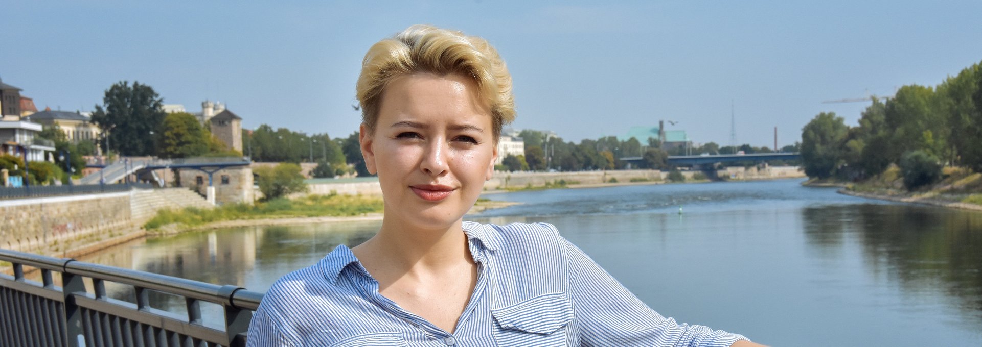 Eine junge blonde Frau steht an der Elbe.