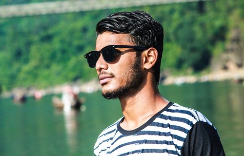 Ein junger Mann mit Sonnenbrille schaut zur Seite.