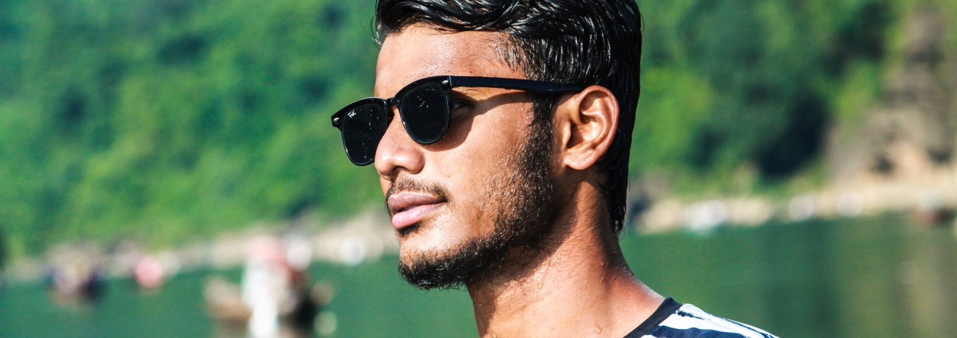Ein junger Mann mit Sonnenbrille schaut zur Seite.