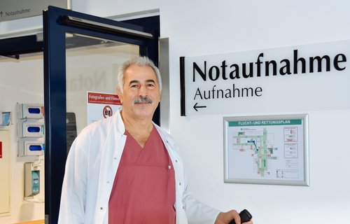 Ein älterer Mann steht im Arztkittel 