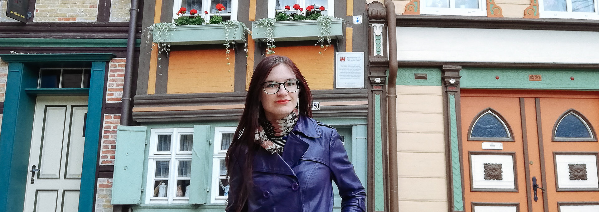 Eine junge Frau steht vor Fachwerkhäusern
