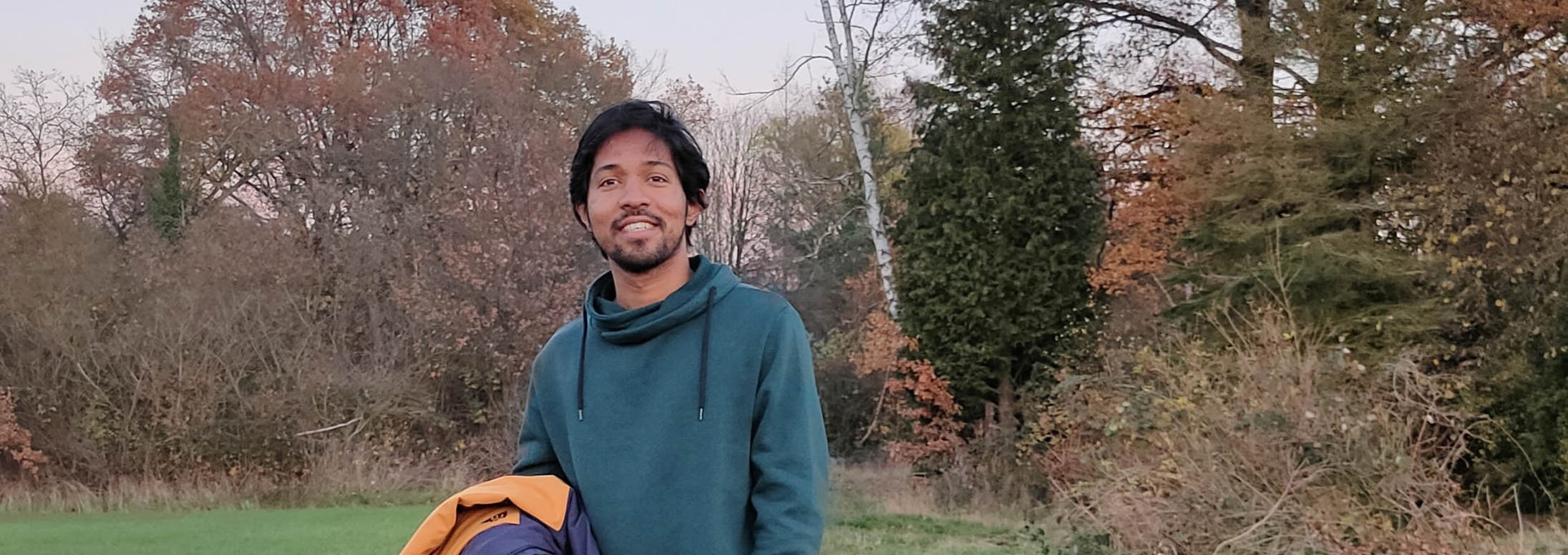 Ein junger Mann aus Indien steht auf einem Waldweg.