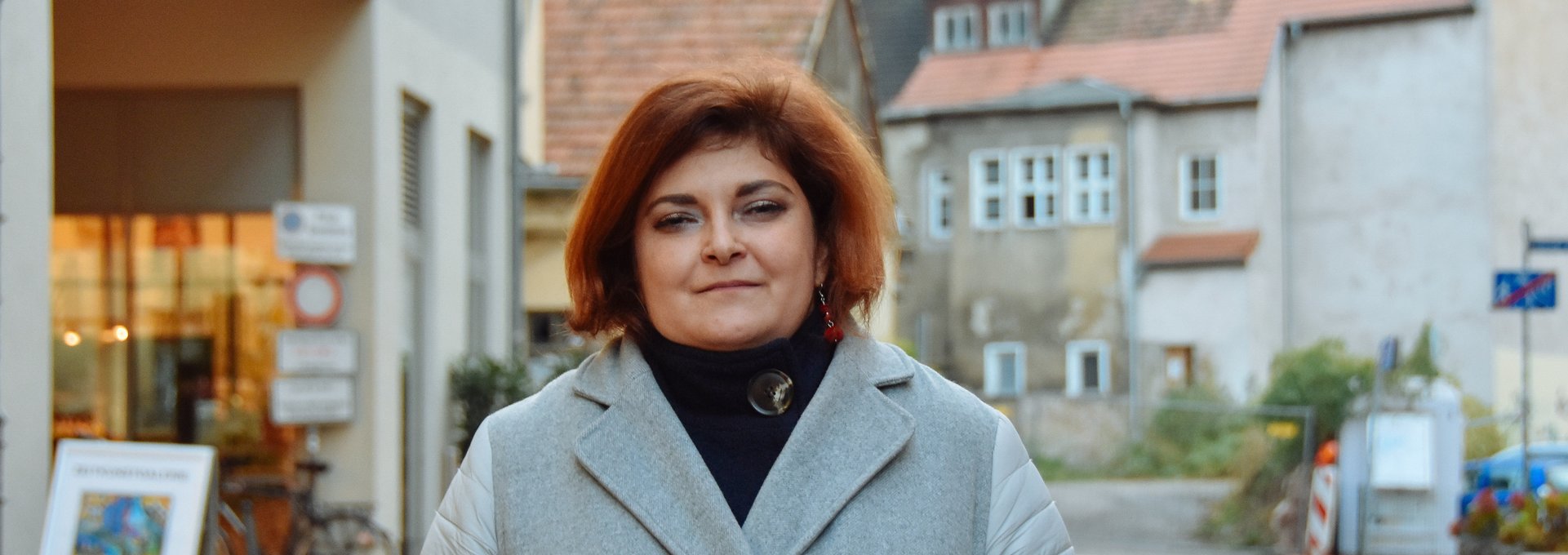 Eine junge Frau steht im Wintermantel auf der Straße.