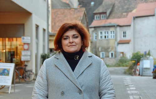Eine junge Frau steht im Wintermantel auf der Straße.