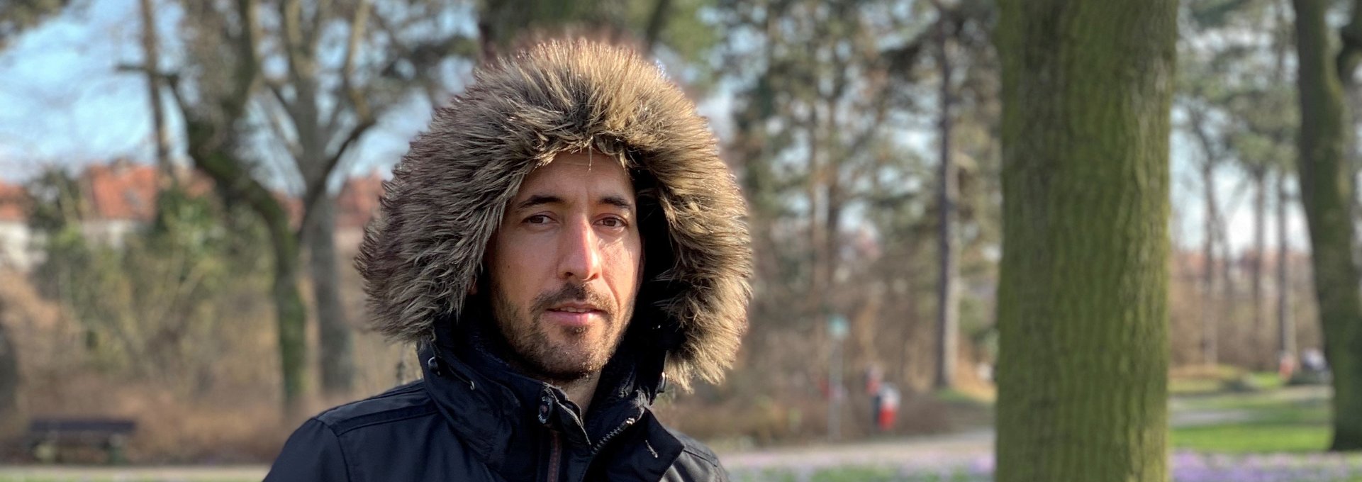 Ein junger Mann trägt eine Jacke mit Kapuze im Park.