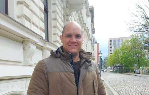 Ein großer, junger Mann steht auf der Straße.