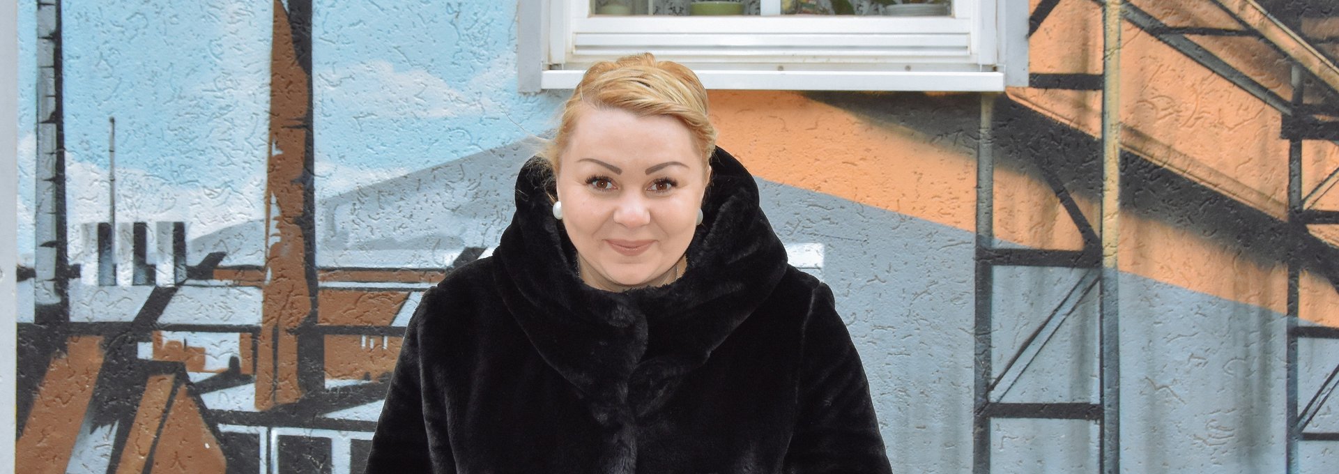 Eine junge Frau mit blonden Haaren grinst frech in die Kamera.