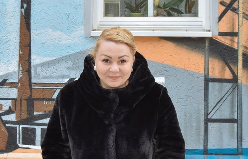 Eine junge Frau mit blonden Haaren grinst frech in die Kamera.