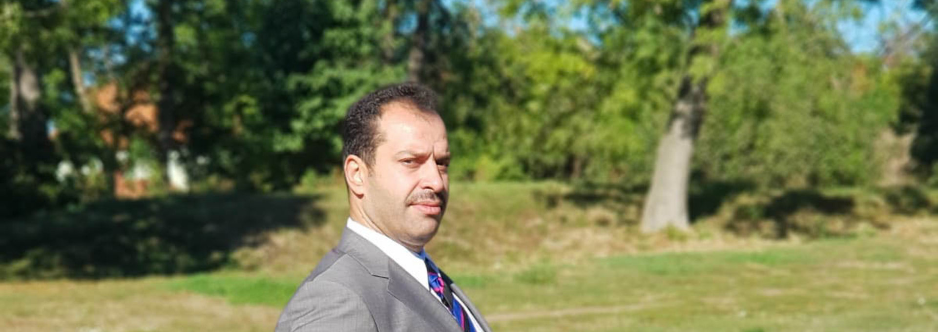 Ein Mann im Anzug steht auf einer Wiese.
