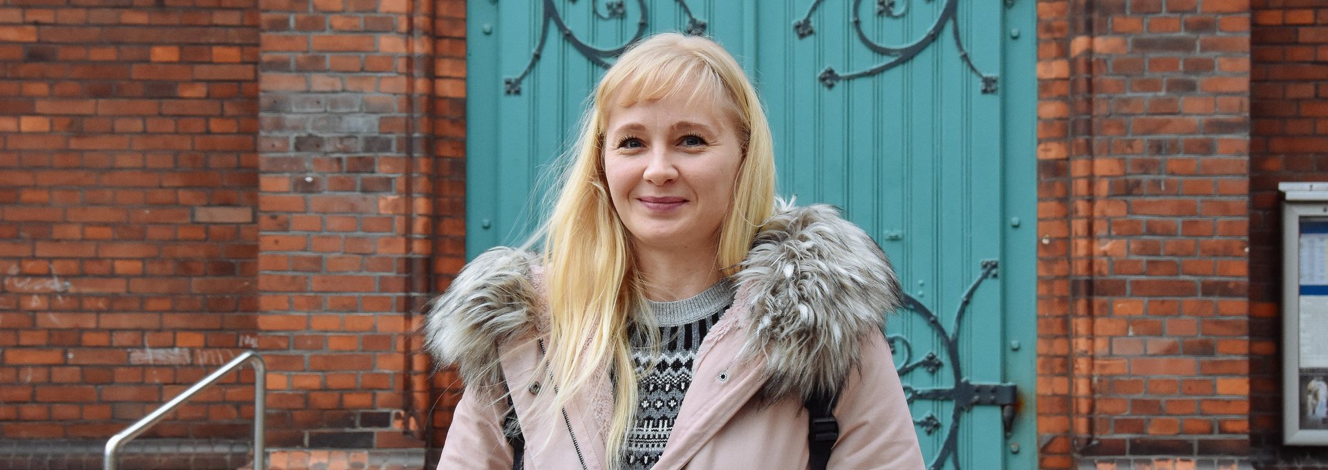 Ein junge blonde Frau steht vor einer Kirche.