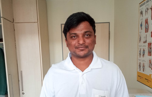 Ein Mann aus Indien steht in einem Raum und trägt eine Ärzteuniform.
