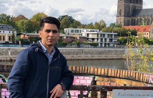 Ein junger Mann steht am Ufer der Elbe.