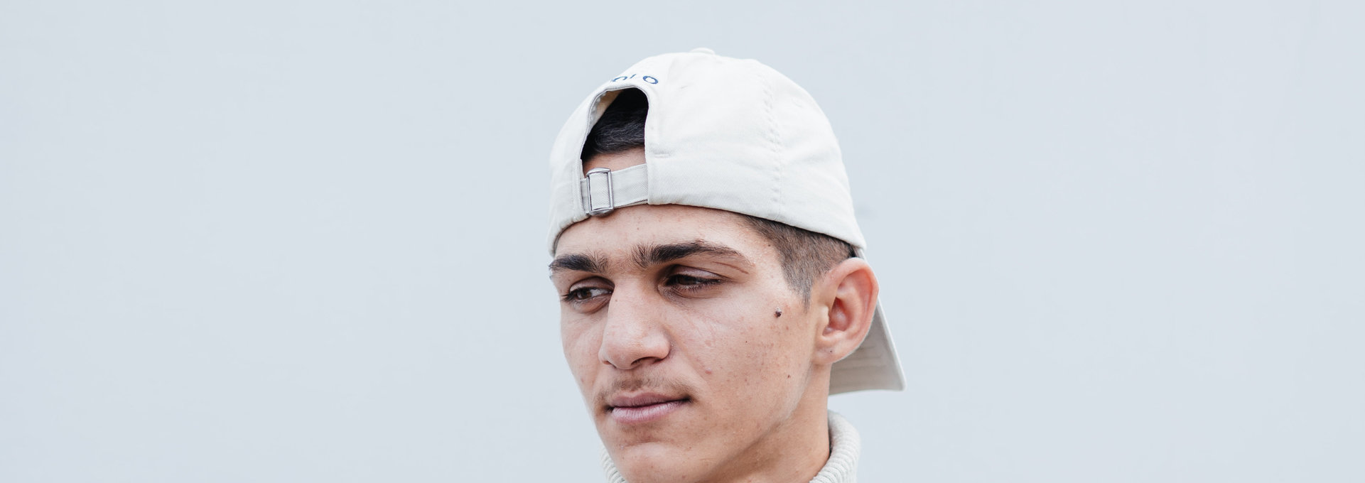 Ein junger Mann mit weißer Cap auf dem Kopf.