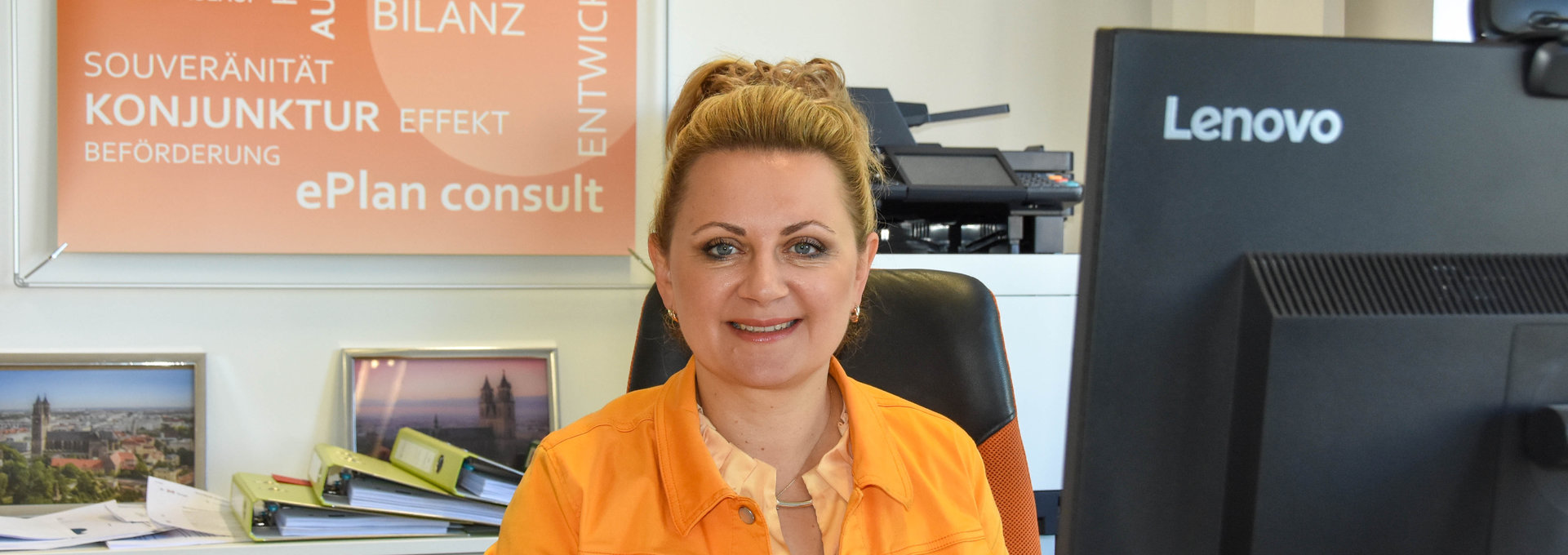 Eine blonde Frau sitzt vor einem Computer.