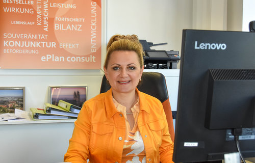 Eine blonde Frau sitzt vor einem Computer.