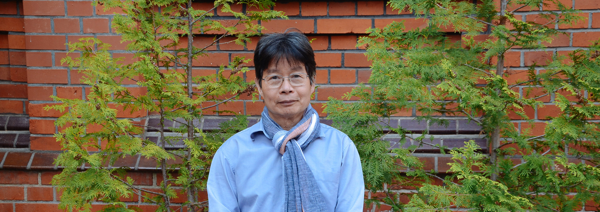 Ein älter Herr aus Vietnam steht vor einer Mauer.